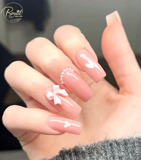 Glossy pink coffin nails with a white bow and pearl details